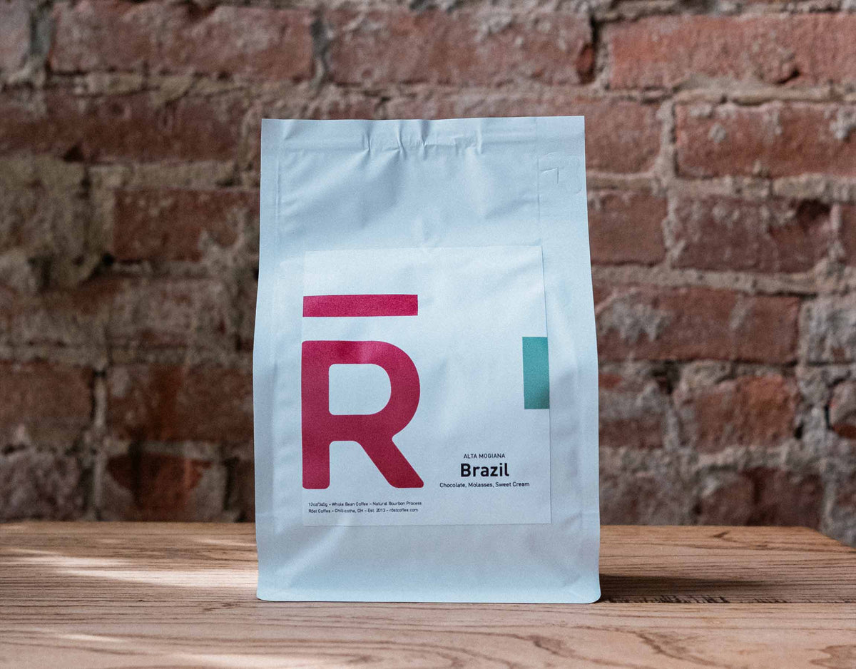 A bag of RŌST whole bean coffee on a wood table against a brick wall