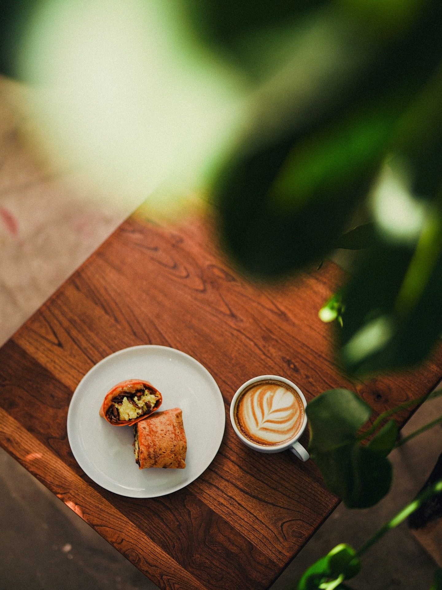 A latte and breakfast on a wood table at RŌST Coffee in Chillicothe