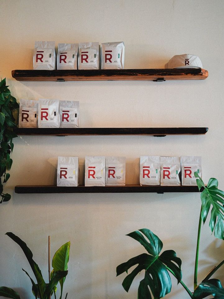 RŌST coffee bags and a RŌST cap on wood shelves